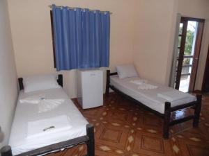 two beds in a room with a blue curtain at POUSADA DO GALEGO in Itaguaí