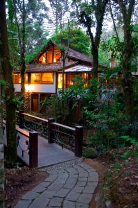 a house with a wooden deck in the woods at Pousada Casa Bonita in Visconde De Maua
