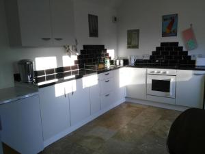 eine Küche mit weißen Schränken und schwarzen Arbeitsplatten in der Unterkunft Garden Cottage in Sleaford