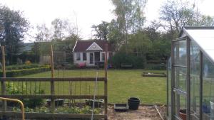 einen Garten mit einem Gewächshaus und einem Haus in der Unterkunft Garden Cottage in Sleaford