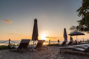 a group of chairs and umbrellas on the beach at sunset at Double - Six, Luxury Hotel - Seminyak in Seminyak