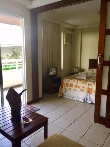 a room with a bed and a table with a cat on it at Apto funcional em frente ao mar in Pirangi do Norte