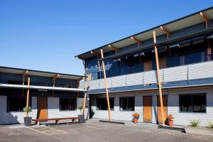 un edificio con bancos en un aparcamiento en Beach House Motel, en Papamoa