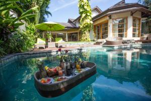 a resort pool with a boat filled with food and drinks at Mayana Villas in Canggu