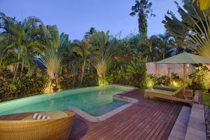 a backyard with a swimming pool and a wooden deck at Mayana Villas in Canggu