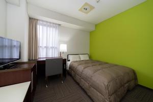 a bedroom with a bed and a desk and a television at Hotel S-Plus Hiroshima Peace Park in Hiroshima