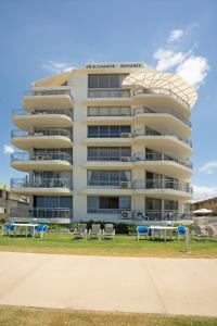 a large white building with chairs in front of it at Oceanside Resort - Absolute Beachfront Apartments in Gold Coast