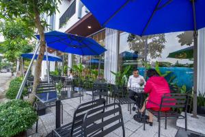 岘港King House Villa Hotel & Spa的坐在桌子下伞下的女人