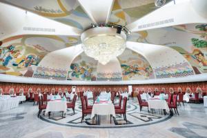 a dining room with tables and chairs and a chandelier at Otrar in Almaty
