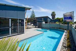 a swimming pool in front of a house at Beach House Motel in Papamoa