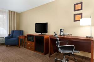a hotel room with a desk with a television and a chair at Baymont by Wyndham Rocky Mount in Rocky Mount