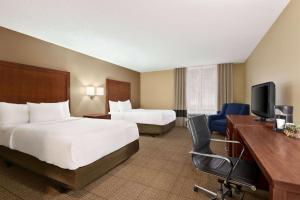 a hotel room with two beds and a desk and a television at Baymont by Wyndham Rocky Mount in Rocky Mount +10 photos