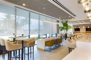 a restaurant with tables and chairs and large windows at Wyndham Garden Ft Lauderdale Airport & Cruise Port in Dania Beach