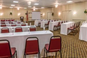 une salle de conférence avec des tables blanches et des chaises rouges dans l'établissement Ramada by Wyndham Triangle/Quantico, à Triangle