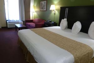 a hotel room with a large bed and a red couch at Travelodge by Wyndham Knoxville East in Knoxville