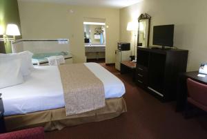 a hotel room with a large bed and a bathroom at Travelodge by Wyndham Knoxville East in Knoxville