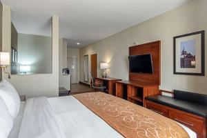 a hotel room with a bed and a desk with a television at Comfort Suites NW Dallas Near Love Field in Dallas