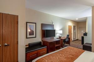 a hotel room with a bed and a desk with a television at Comfort Suites NW Dallas Near Love Field in Dallas