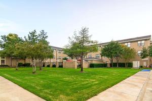 a green yard with trees in front of a building at Comfort Suites NW Dallas Near Love Field in Dallas
