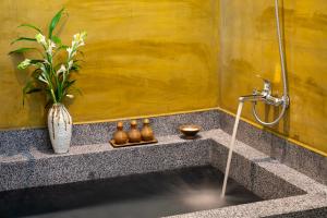 a bathroom with a shower and a vase with a plant at Khmer House Resort in Siem Reap