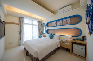 pokój hotelowy z dużym łóżkiem i oknem w obiekcie 岸戀民宿 墾丁船帆石 w mieście Eluan