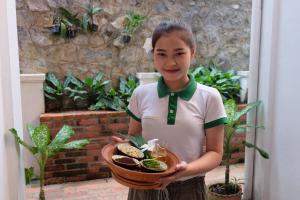 a young girl holding a bowl of food at Mekong Riverview Hotel in Luang Prabang