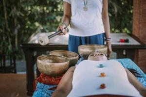 Una mujer acostada en una mesa mientras una mujer está cocinando en Amatara Agung Raka, en Ubud