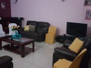 sala de estar con muebles de cuero negro y TV en Sheevy"s Bed N Breakfast, en Fort Portal