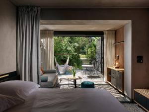a bedroom with a bed and a balcony with a hammock at Ekies All Senses Resort, a Member of Design Hotels in Vourvourou +37 photos