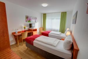 ein Hotelzimmer mit 2 Betten und einem Schreibtisch in der Unterkunft Hotel Leo Mühlhausen in Mühlhausen
