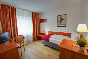 a hotel room with a bed and a desk at Hotel Leo Mühlhausen in Mühlhausen