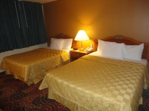 2 camas en una habitación de hotel con lámpara y teléfono en Americas Best Value Inn Santa Rosa, New Mexico, en Santa Rosa