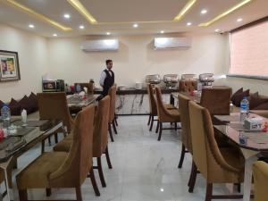 a man standing in a restaurant with tables and chairs at Hotel Avalon Suites in Multan