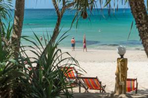 a beach with chairs and people in the water at Lanta Miami Resort - SHA Extra Plus in Ko Lanta
