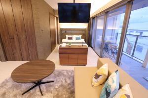 那覇市にあるTabinoteitaku Okinawa Nahaのベッド、テーブル、テレビが備わる客室です。