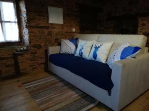 un sofá con almohadas azules y blancas. en Casinha do Talasnal en Lousã