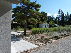 einen Garten mit Kiefer und Bürgersteig in der Unterkunft Au Coin des Cerisiers in Montclus