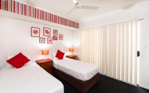 two beds in a room with red pillows at Cairns City Apartments in Cairns