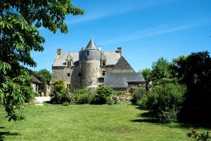 um velho castelo sentado no topo de um exuberante campo verde em Manoir de la Sénéchaussée de Lantiern em Arzal