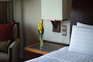 a vase filled with flowers on top of a bed at Kerry Hotel Pudong, Shanghai in Shanghai