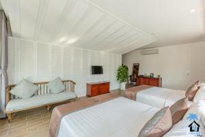 a bedroom with two beds and a couch and a tv at Cottage Village in Phu Quoc