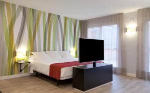 a bedroom with a bed with a flat screen tv at Vértice Sevilla in Seville