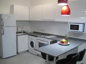 a kitchen with white appliances and a table with a bowl of fruit at Angel's Apartment at Caesar Resort in Trikomo