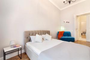 リヴィウにあるChopin Apartment in the center of Lvivの白いベッドルーム(大型ベッド1台、青い椅子付)