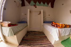 two beds in a small room with a rug at Takela Kato Guest House in Aswan