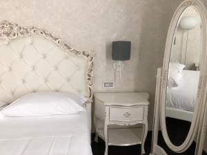 1 dormitorio con cama blanca y espejo en Palazzo Favacchio - Patanè en Scicli
