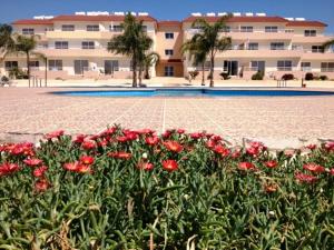 einen Garten mit roten Blumen vor einem Gebäude in der Unterkunft Nissi 3 C4 Pool View Apt in Ayia Napa