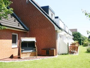 a red brick building with a deck with a grill at Haus Südwind in Büsum