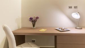 a desk with a vase of flowers and a plate of candy at Scicli Albergo Diffuso in Scicli