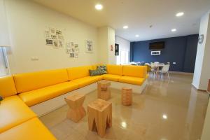 salon z żółtą kanapą i stołami w obiekcie Micampus Málaga w Maladze